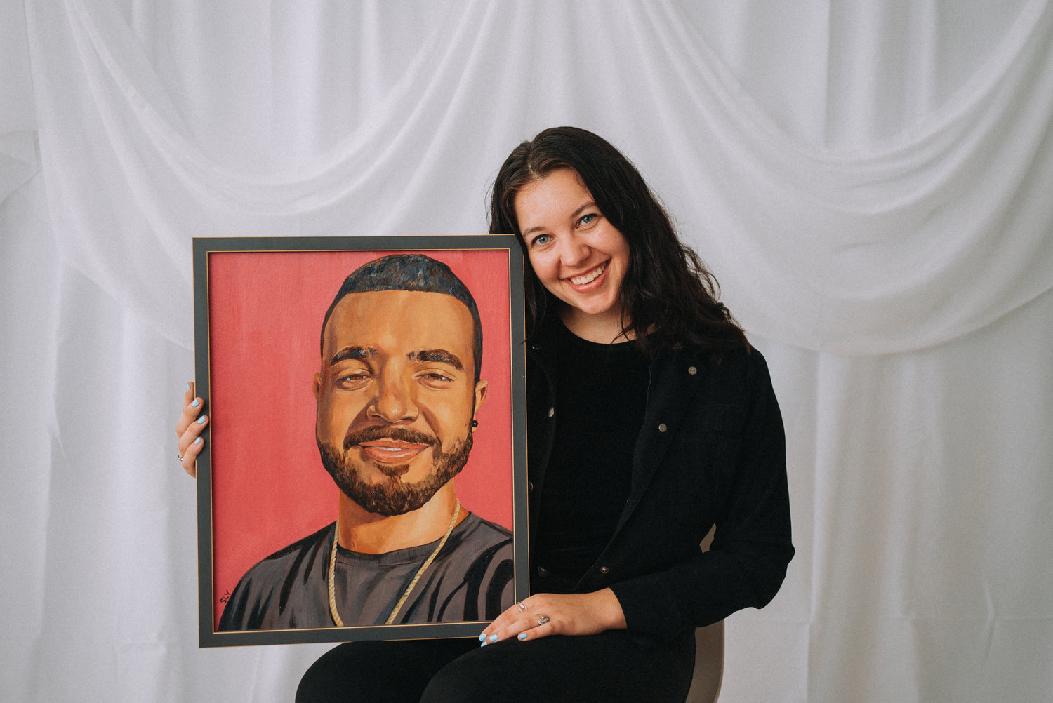 Artist Shayna Yacyshyn holding up a custom portrait paitning to her side