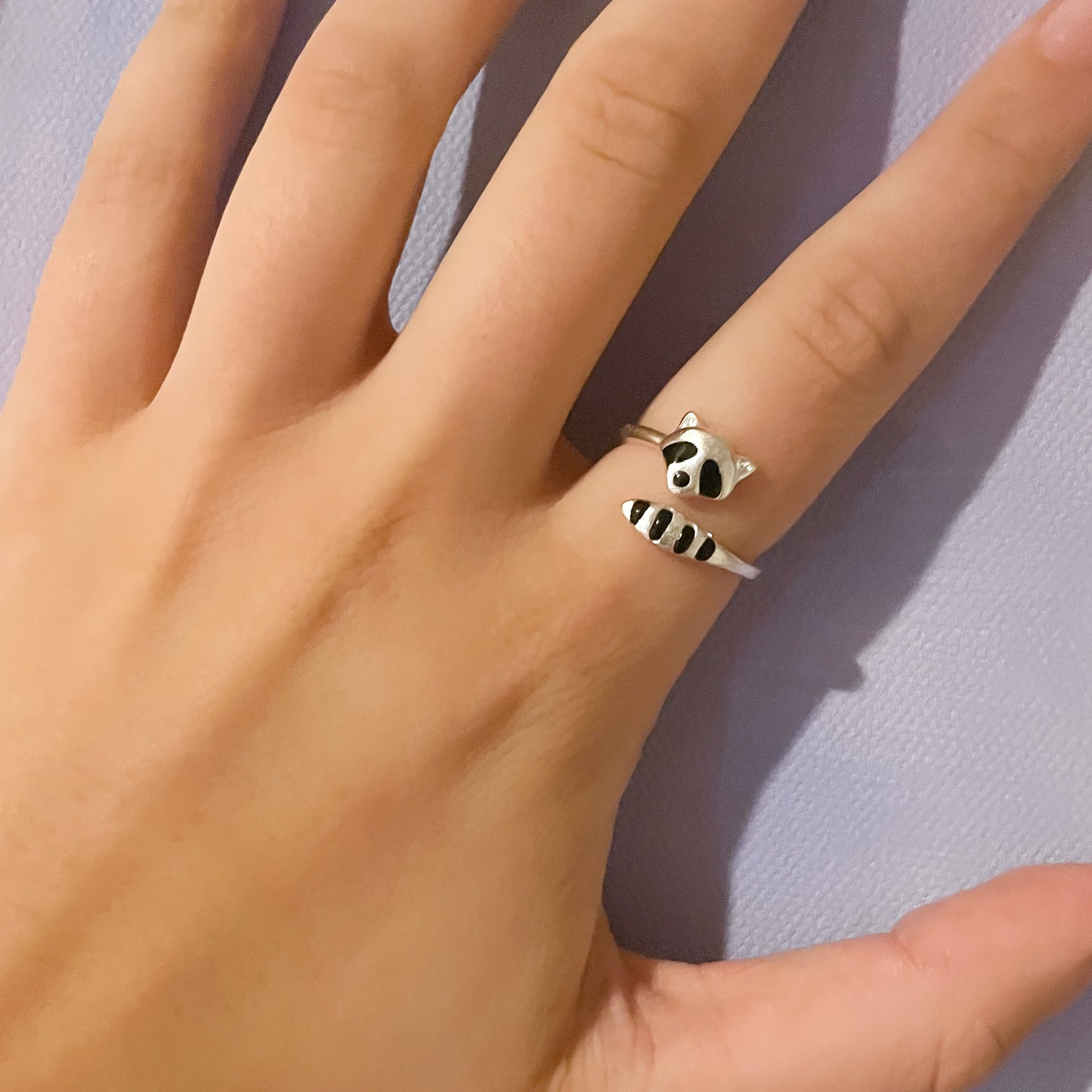 A hand with the raccoon ring on the pointer finger