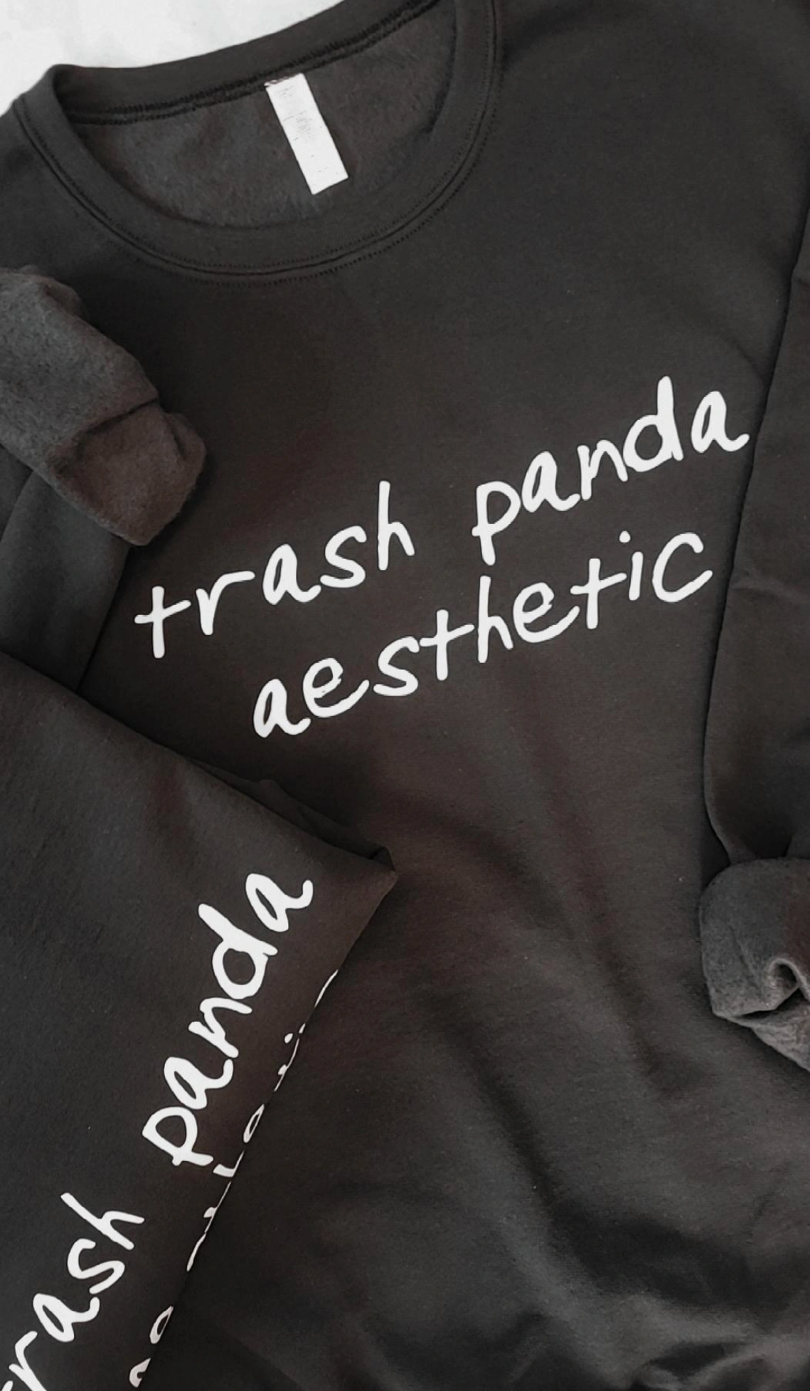 Two black sweatshirts with white text that reads, "trash panda aesthetic" written across the chest